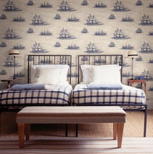 Decoración de dormitorio, papel pintado con detalles náuticos, dibujos de barcos azules sobre fondo blanco colcha a cuadros blanco y azul